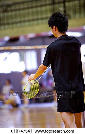 Stock Image - Man prepares to serve during a game of badminton.. Fotosearch