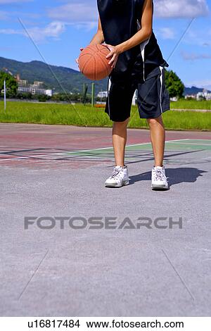 Picture - Teenage boy preparing to throw basketball, low section. Fotosearch
