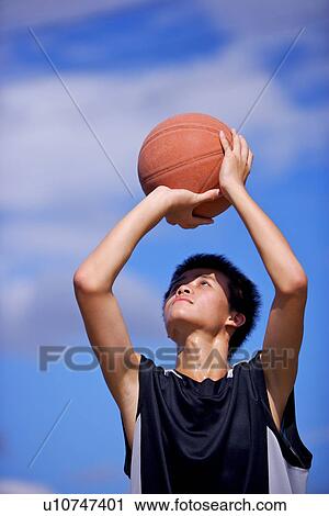 Stock Image - Teenage boy preparing to throw basketball. Fotosearch