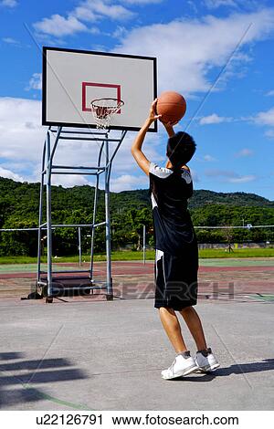 Stock Image - Teenage boy preparing to throw basketball. Fotosearch