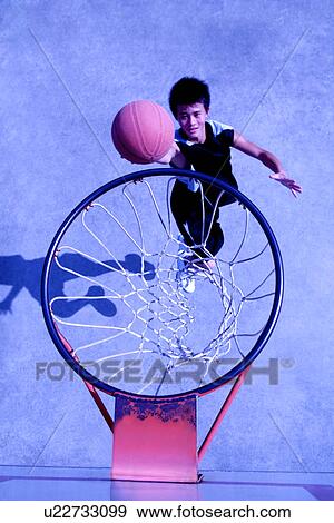 Stock Photo - Teenage boy shooting a basketball, high angle view. Fotosearch