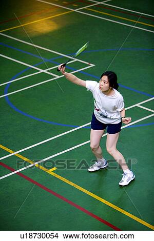 Woman poised to hit shuttlecock with badminton racket View Large Photo Image Picture - Woman poised to hit shuttlecock with badminton racket. Fotosearch