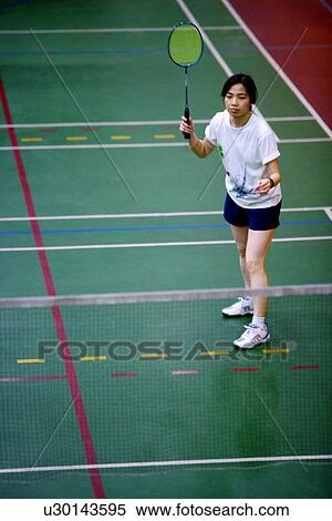 Stock Photography - Woman poised to hit shuttlecock with badminton racket. Fotosearch