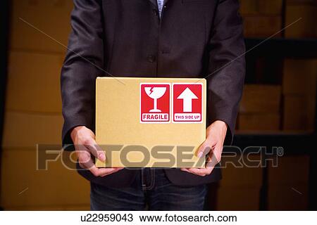 Stock Image - Man holding box, mid section. Fotosearch