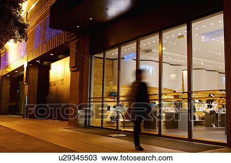 Stock Image - One person walking past shopping mall. Fotosearch
