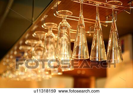 Wine glasses hanging upside down in row View Large Photo Image Stock Photo - Wine glasses hanging upside down in row. Fotosearch