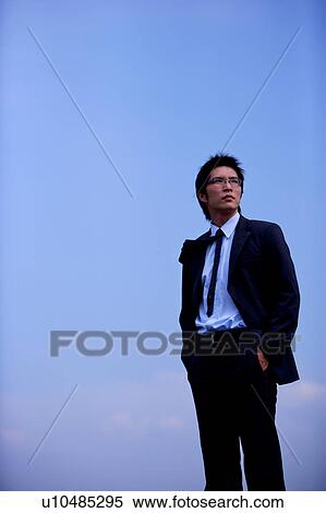 Stock Photography - Young businessman against blue sky. Fotosearch