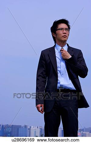 Stock Photo - Young businessman, buildings in the background. Fotosearch
