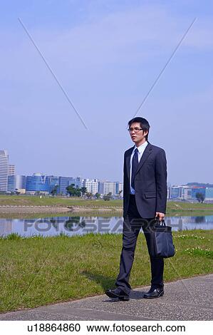 Young businessman holding briefcase walking outdoors View Large Photo Image Stock Image - Young businessman holding briefcase walking outdoors. Fotosearch