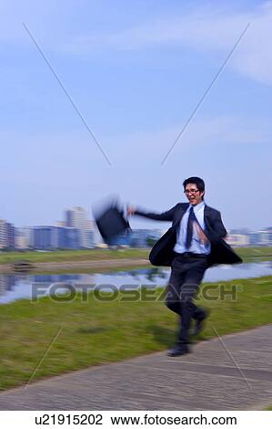 Stock Image - Young businessman holding briefcase. Fotosearch