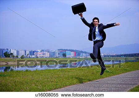 Young businessman holding briefcase jumping outdoors View Large Photo Image Stock Photography - Young businessman holding briefcase jumping outdoors. Fotosearch