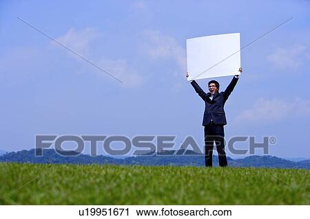 Young businessman holding whiteboard outdoors View Large Photo Image Stock Image - Young businessman holding whiteboard outdoors. Fotosearch