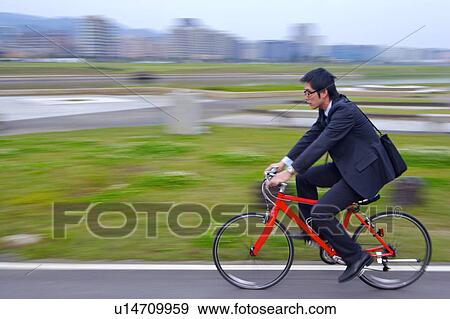 Young businessman riding bike outdoors View Large Photo Image Stock Photo - Young businessman riding bike outdoors. Fotosearch