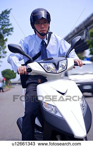 Stock Image - Young businessman riding motorcycle on street. Fotosearch