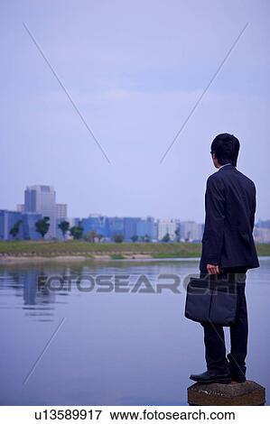 Stock Photo - Young businessman standing at water's edge. Fotosearch