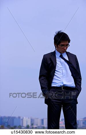 Stock Image - Young businessman with hands in pockets. Fotosearch