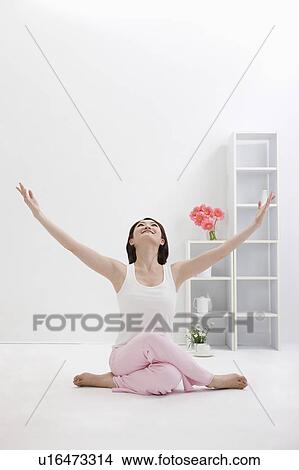 Picture - Young woman doing yoga with arms outstretched. Fotosearch