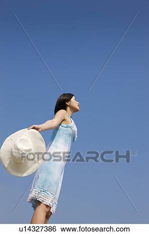 Stock Photograph - Young woman holding a sunhat and looking away. Fotosearch