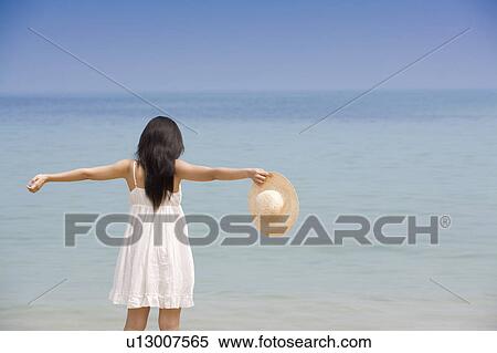 Young woman holding a sunhat with arms outstretched View Large Photo Image Stock Photography - Young woman holding a sunhat with arms outstretched. Fotosearch