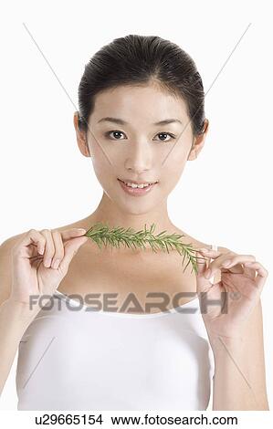 Picture - Young woman holding green leaves and smiling. Fotosearch