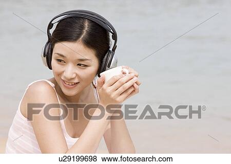 "Young woman listening to music and holding teacup, portrait" View Large Photo Image Stock Photo - "Young woman listening to music and holding teacup, portrait". Fotosearch