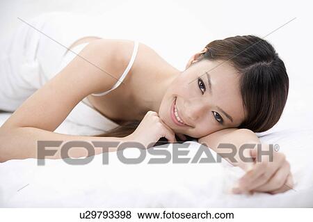 Stock Photo - Young woman lying on front and looking at the camera. Fotosearch