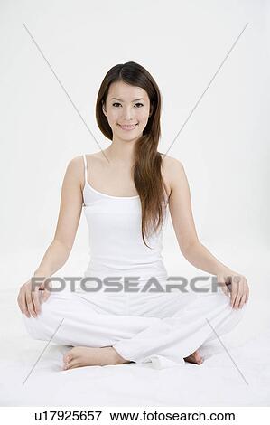 Stock Photo - Young woman making lotus position and smiling. Fotosearch
