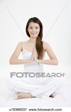 Stock Photo - Young woman making lotus position and smiling. Fotosearch