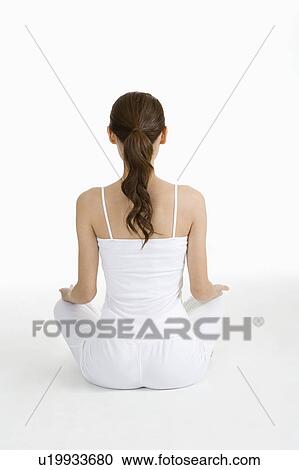 Stock Image - "Young woman making lotus position, rear view". Fotosearch