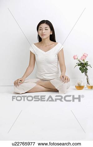 Stock Photo - Young woman making lotus position with eyes closed. Fotosearch