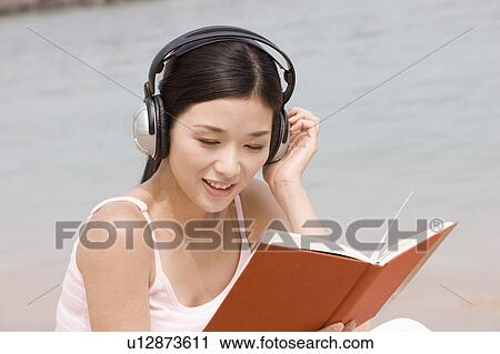 Young woman reading book and listening to music View Large Photo Image Stock Image - Young woman reading book and listening to music. Fotosearch