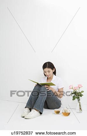 Young woman sitting and reading book View Large Photo Image Stock Photo - Young woman sitting and reading book. Fotosearch