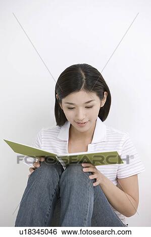 Stock Photograph - Young woman sitting and reading book. Fotosearch