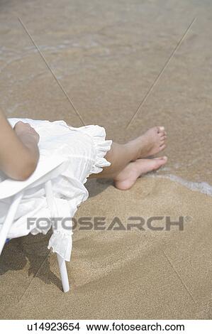Picture - Young woman sitting on beach. Fotosearch
