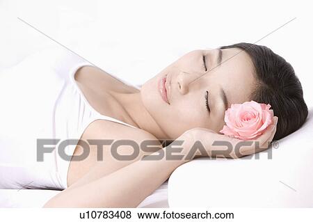 Stock Photo - Young woman sleeping and holding a flower in hand. Fotosearch