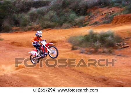 Picture - Young man motocross over field.. Fotosearch
