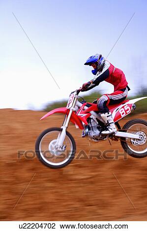 Stock Image - Young man motocross over field.. Fotosearch