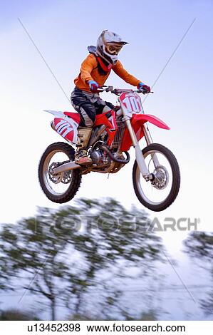 Stock Photo - Young man motocross over field.. Fotosearch
