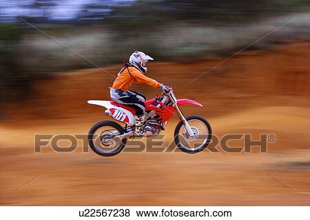Stock Photo - Young man motocross over field.. Fotosearch
