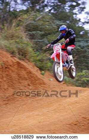 Stock Photo - Young man motocross over field.. Fotosearch