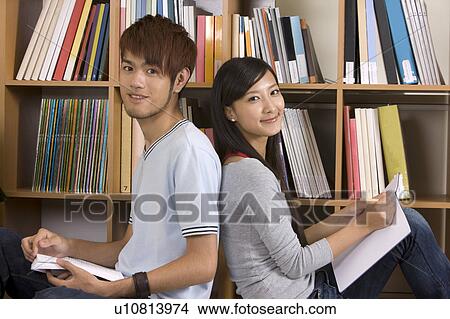 Picture - Schoolboy and schoolgirl sitting with back to back and looking at the camera. Fotosearch