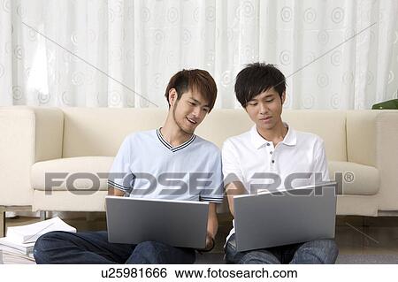 Stock Photograph - Schoolboys using laptop and discussing together. Fotosearch