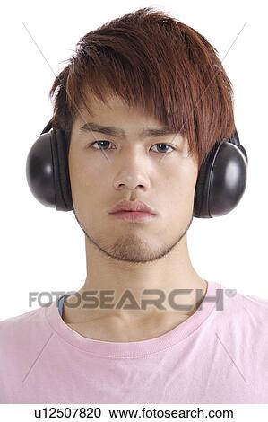 Stock Image - "Teenager boy listening music and looking at the camera, portrait". Fotosearch