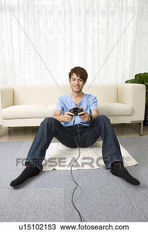Stock Image - "Teenager boy sitting and playing video game, portrait". Fotosearch