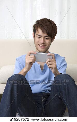 Stock Image - "Teenager boy sitting and playing video game, portrait". Fotosearch
