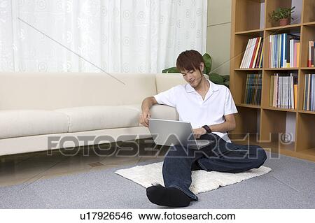 Teenager boy sitting on the floor and using laptop View Large Photo Image Stock Photograph - Teenager boy sitting on the floor and using laptop. Fotosearch