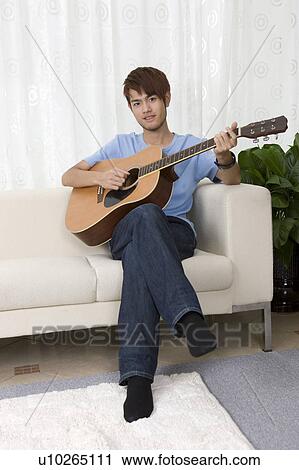 "Teenager boy sitting on the sofa and playing guitar, portrait" View Large Photo Image Stock Image - "Teenager boy sitting on the sofa and playing guitar, portrait". Fotosearch