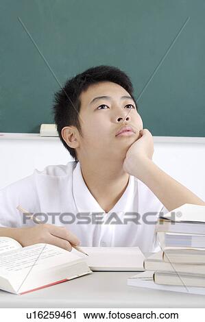 Stock Image - Teenager boy sitting with hand on chin and meditating. Fotosearch
