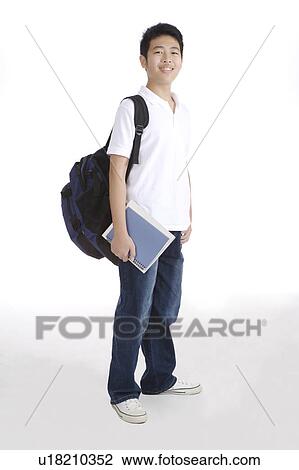 Stock Image - "Teenager boy standing and holding book, portrait". Fotosearch