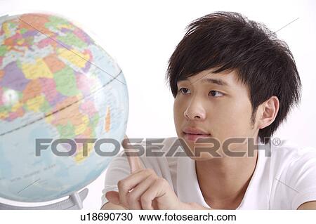 Young man pointing at desktop globe View Large Photo Image Stock Image - Young man pointing at desktop globe. Fotosearch